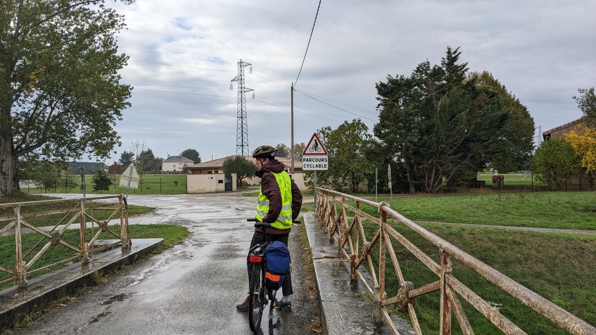 A cyclist on a bridge in front of a sign for a cycle path