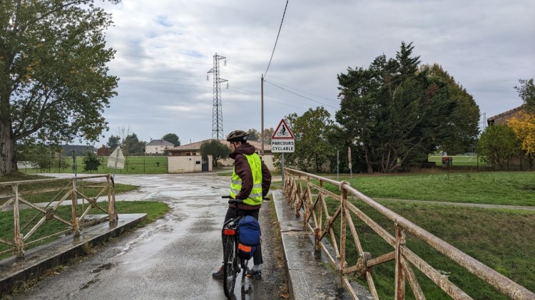 A cyclist on a bridge in front of a sign for a cycle path