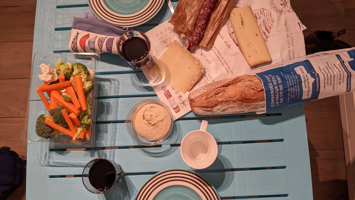 Wine, cheese, vegetable and saucisson on a small blue table